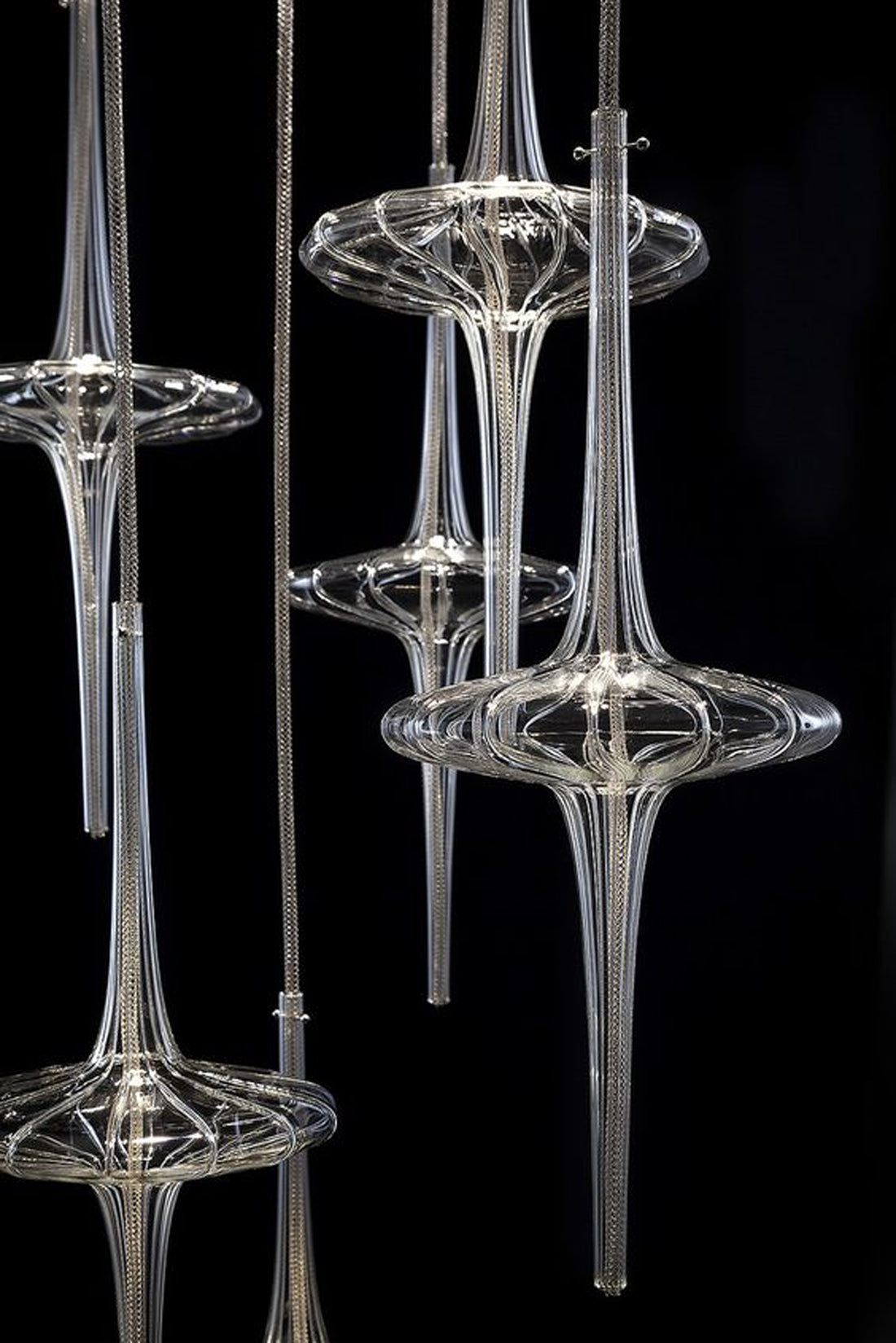 A group of glass sculptures hanging against a black backdrop.