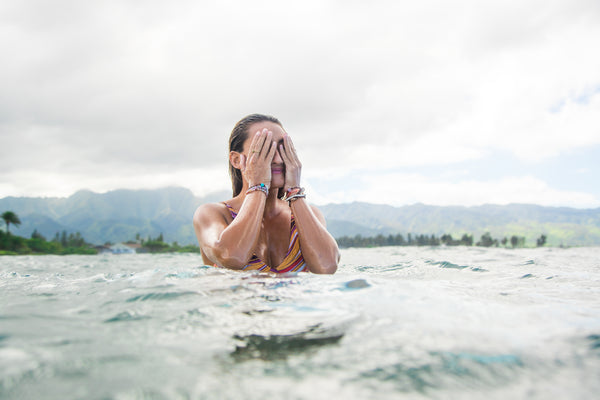 Surfer girl Brittany Penaroza wiping the salt water off her face in ocean