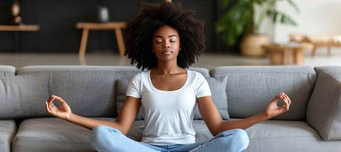 A beautiful lady sitting on a coach in the lotus position as she practices meditation.