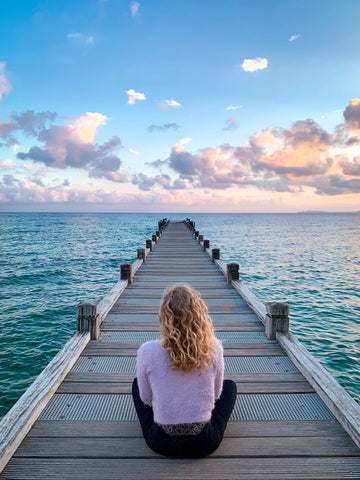 Woman sitting on a dock facing the water