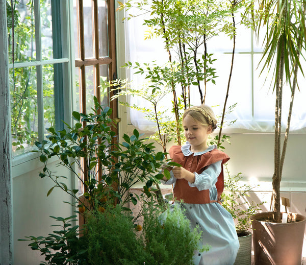 Happy kid interacting with safe and child-friendly indoor plants, fostering a love for nature and a healthier living space.