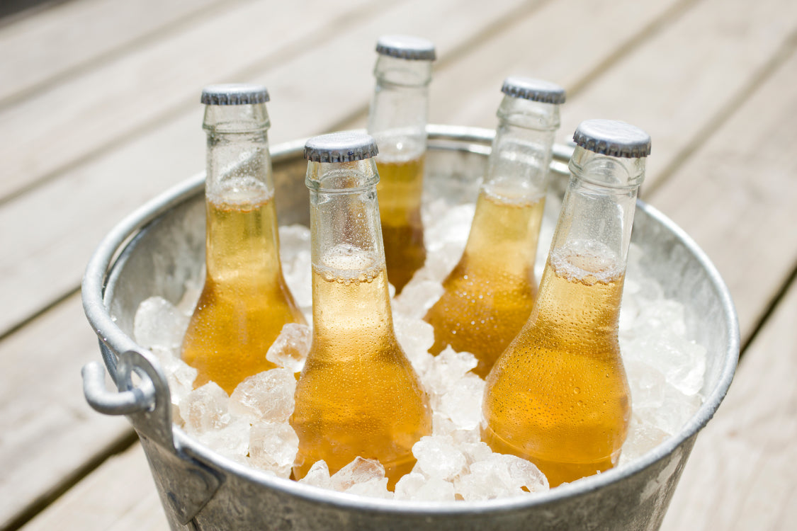 Chilled beer bottles resting in a galvanized bucket of ice, suggesting a refreshing, hydrating drink option.