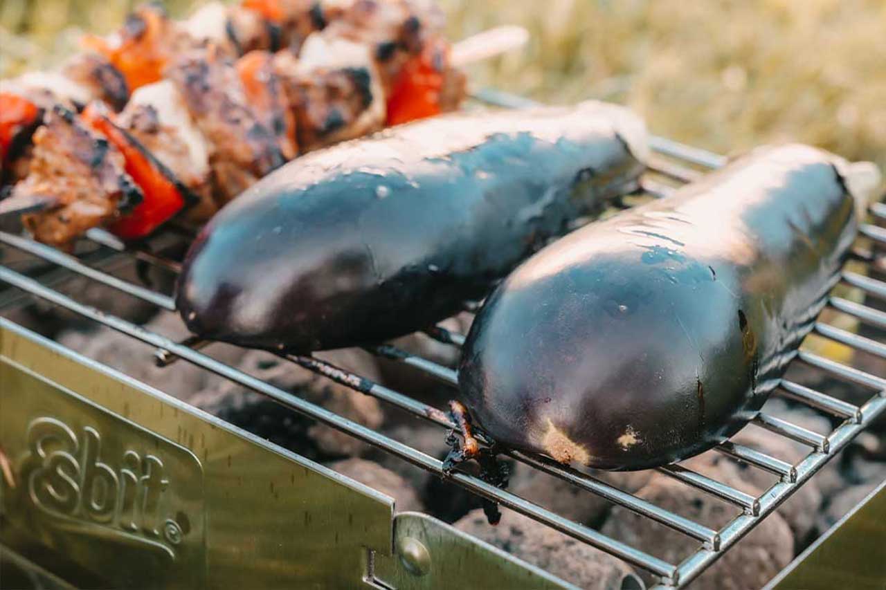 Esbit Mehrweg-Holzkohlegrill aus Edelstahl beim Grillen von Aubergine