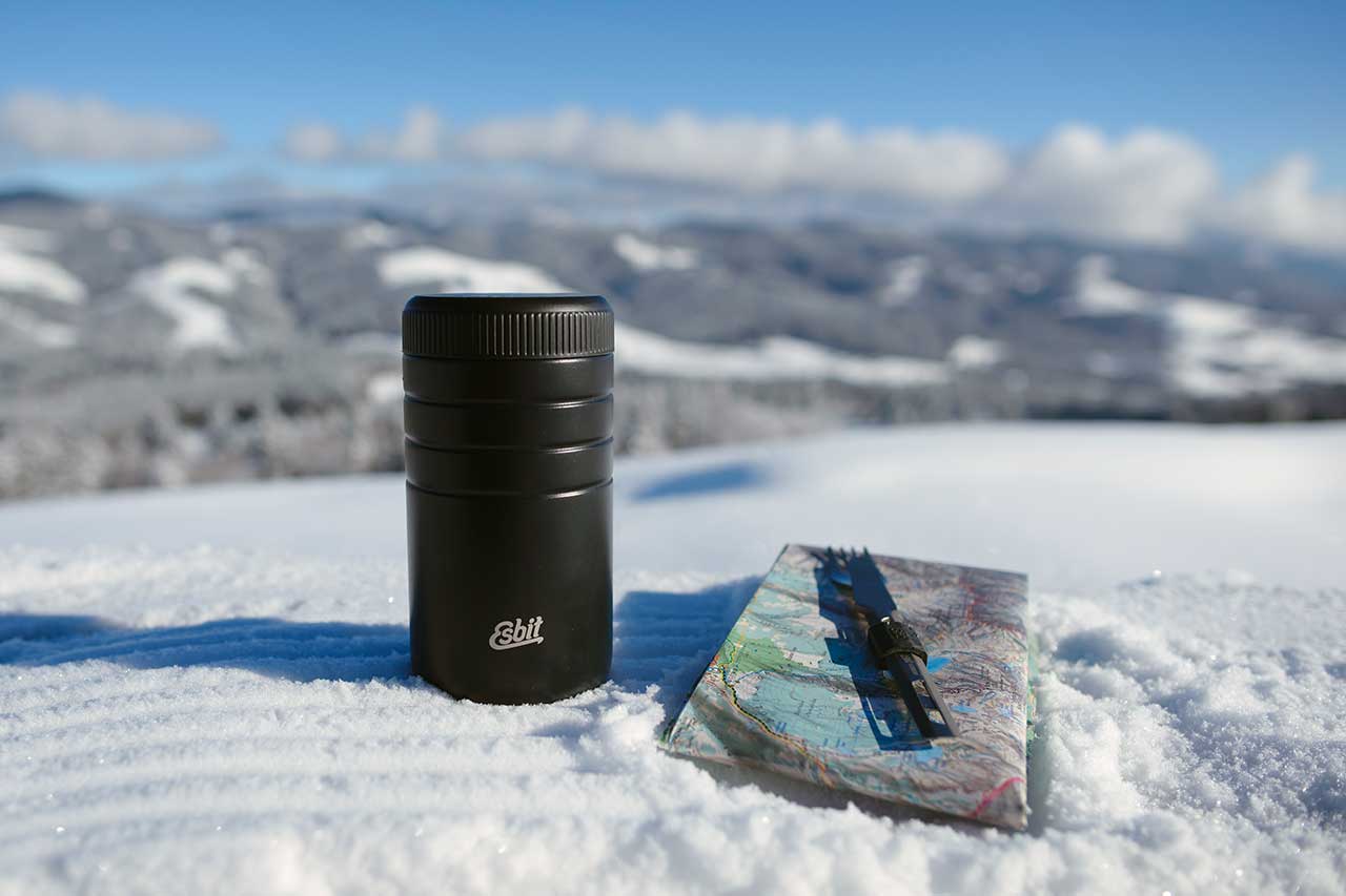 Esbit MAJORIS thermal container in black 550 ml in the snow on the mountain