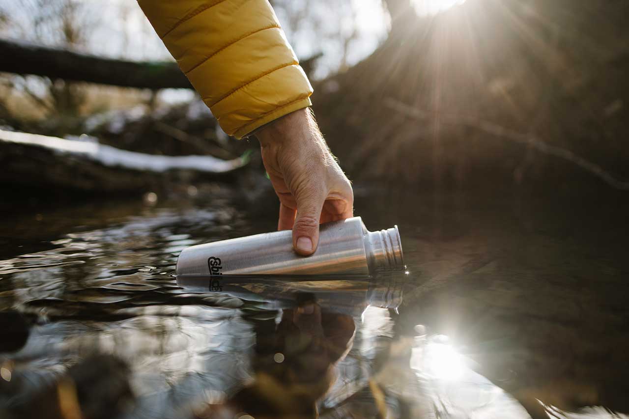 Esbit SCULPTOR Trinkflasche in Edelstahl 1000 ml beim Auffüllen am Fluss