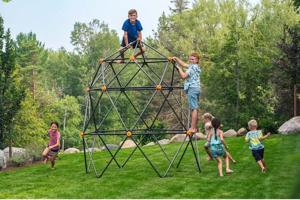 Six young kids playing on and around a geometric climbing dome.
