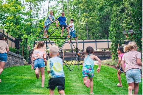 Six kids running to a climbing dome with three kids on it.