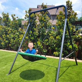 A kid happily on a swing set.