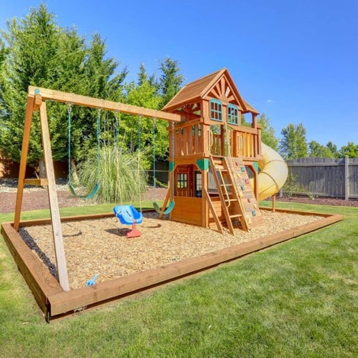 A wooden swing set located on soft surfacing and safely away from impeding structures.