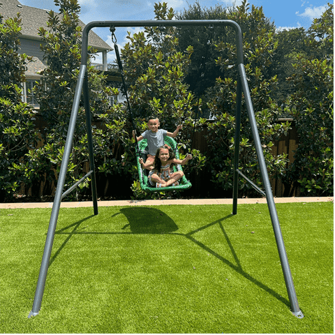 Two kids swinging on a green boat swing.