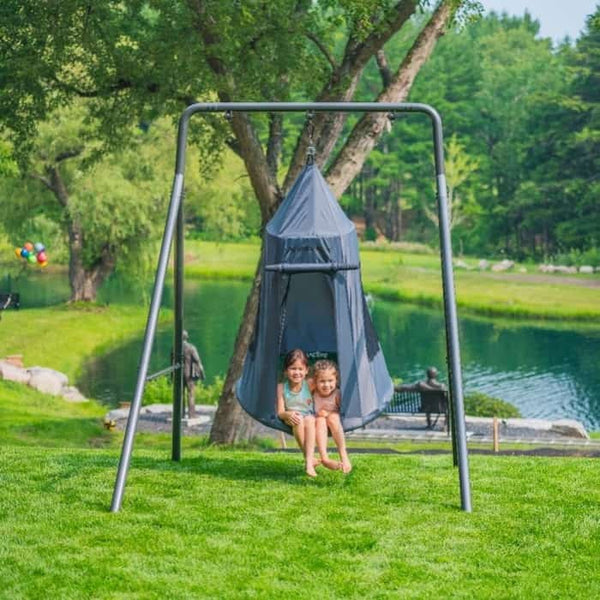 Two little kids sitting in a grey tent swing on a single swing set.