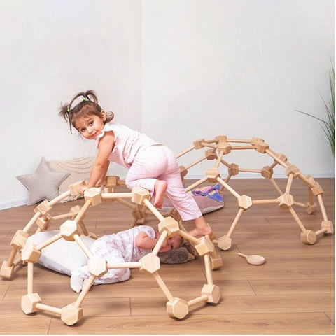 Two young children playing on a wooden climbing dome.