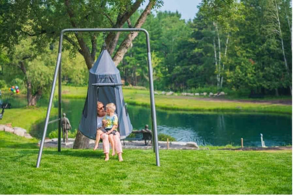 A mother and her son in a tent swing on a swing set.