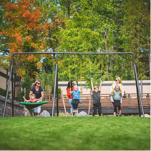 Kids playing on a swing set while their parents stand behind and push.