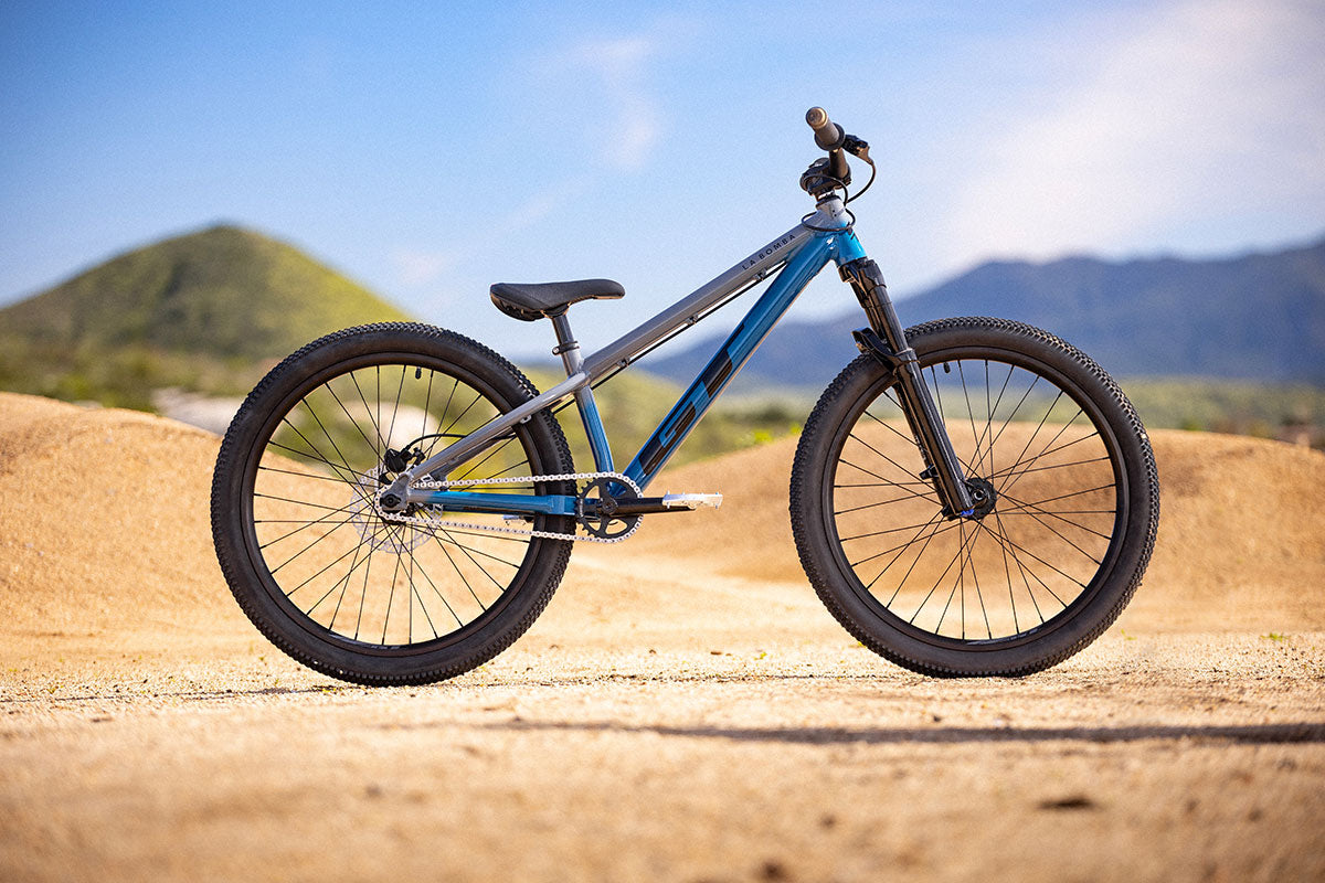 Profile view of bicycle on dirt with mountains in background
