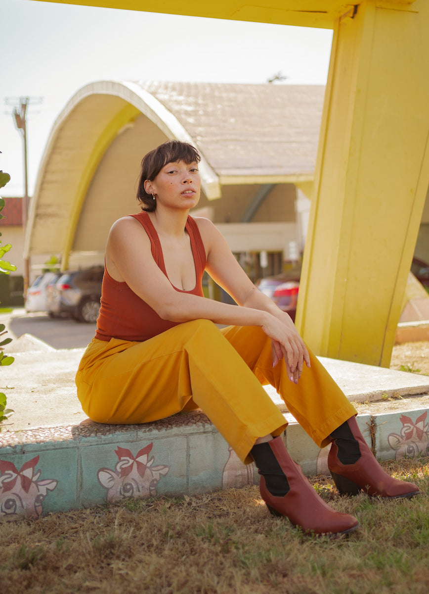 Tiara is wearing Cropped Tank Top in Burnt Terracotta and Organic Trousers in Mustard Yellow