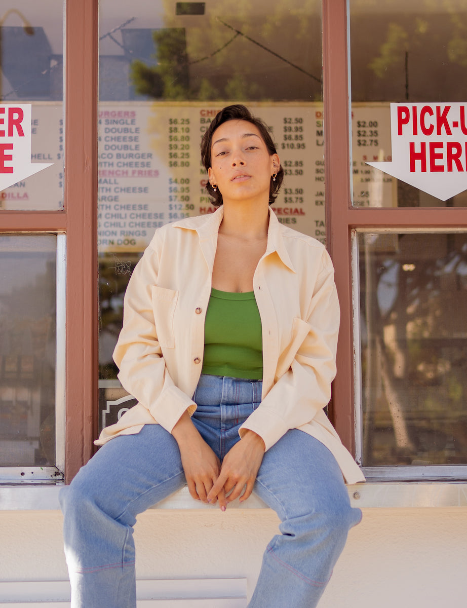 Tiara is wearing Oversize Overshirt in Vintage Off-White, Cropped Tank Top in Lawn Green, and Carpenter Jeans in Light Wash