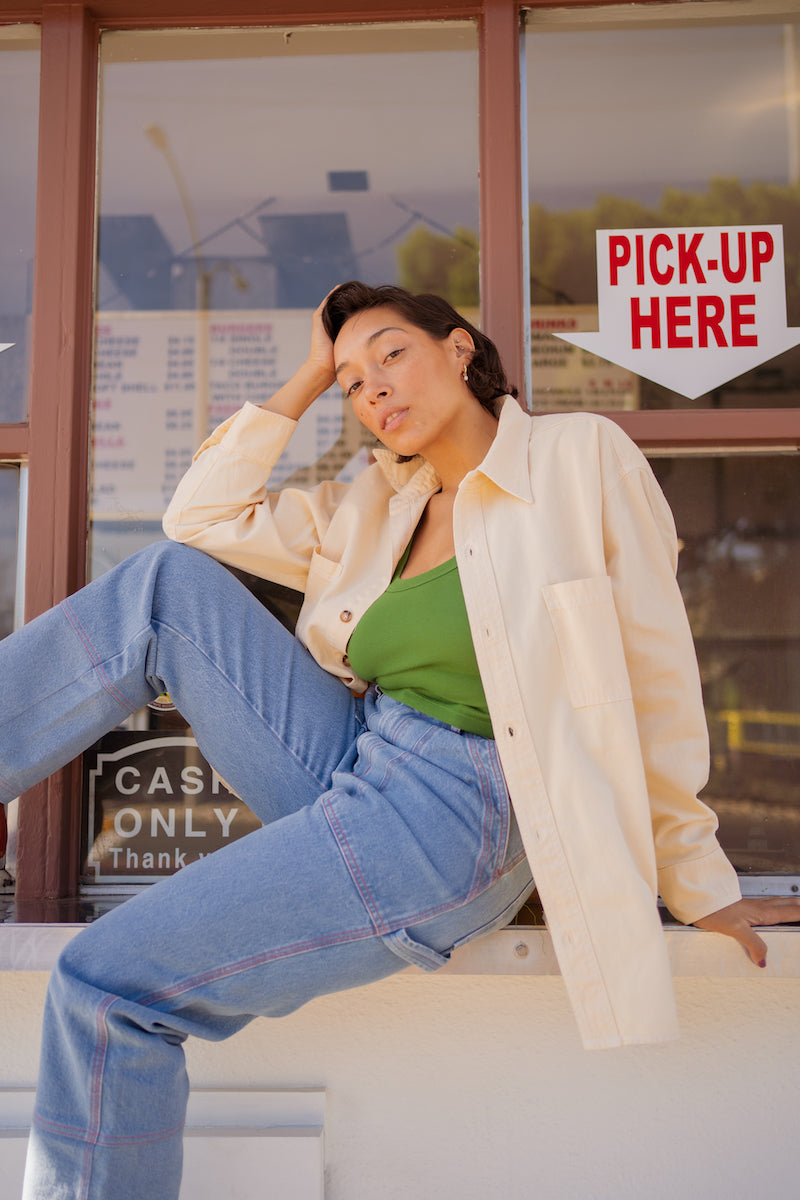 Tiara is wearing Oversize Overshirt in Vintage Off-White, Cropped Tank Top in Lawn Green, and Carpenter Jeans in Light Wash