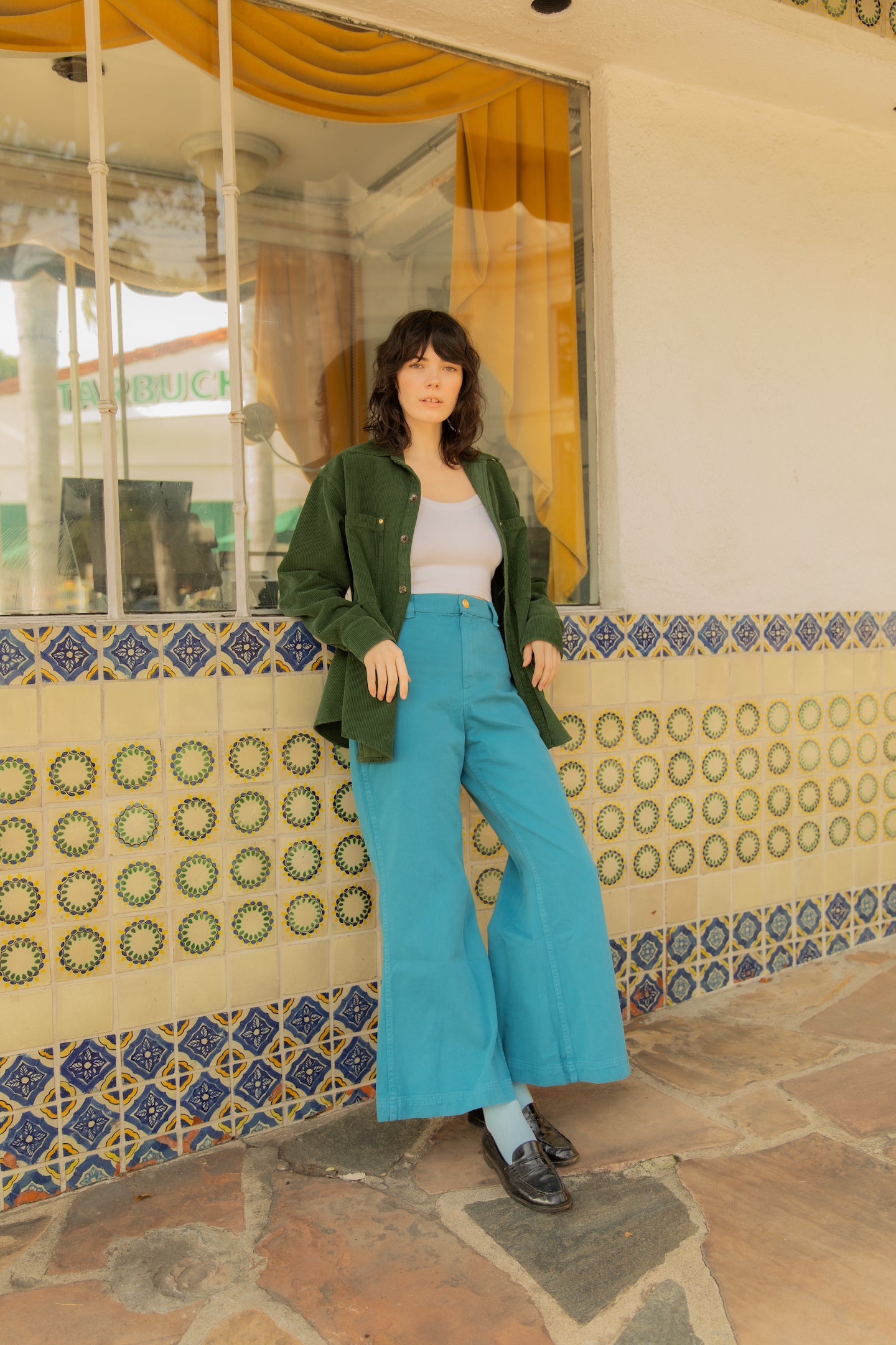 Dani is wearing Corduroy Overshirt in Swamp Green, Cropped Cami in Vintage Off-White and Bell Bottoms in Marine Blue