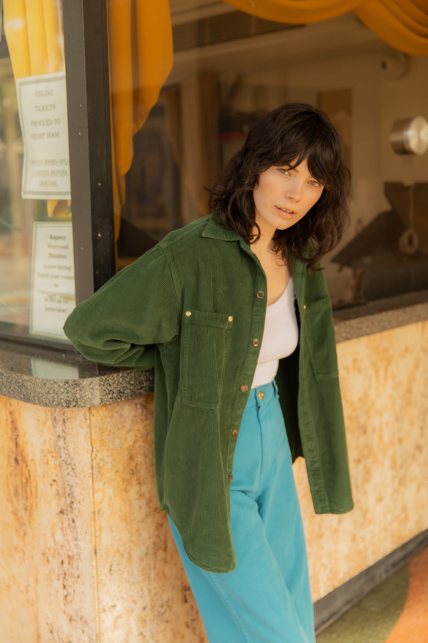 Dani is wearing Corduroy Overshirt in Swamp Green, Cropped Cami in Vintage Off-White and Bell Bottoms in Marine Blue