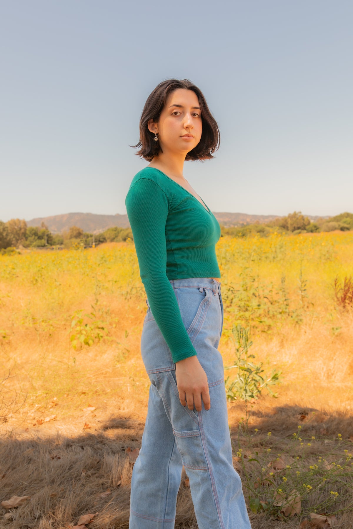 Betty is wearing Long Sleeve V-Neck in Hunter Green and Carpenter Jeans in Light Wash