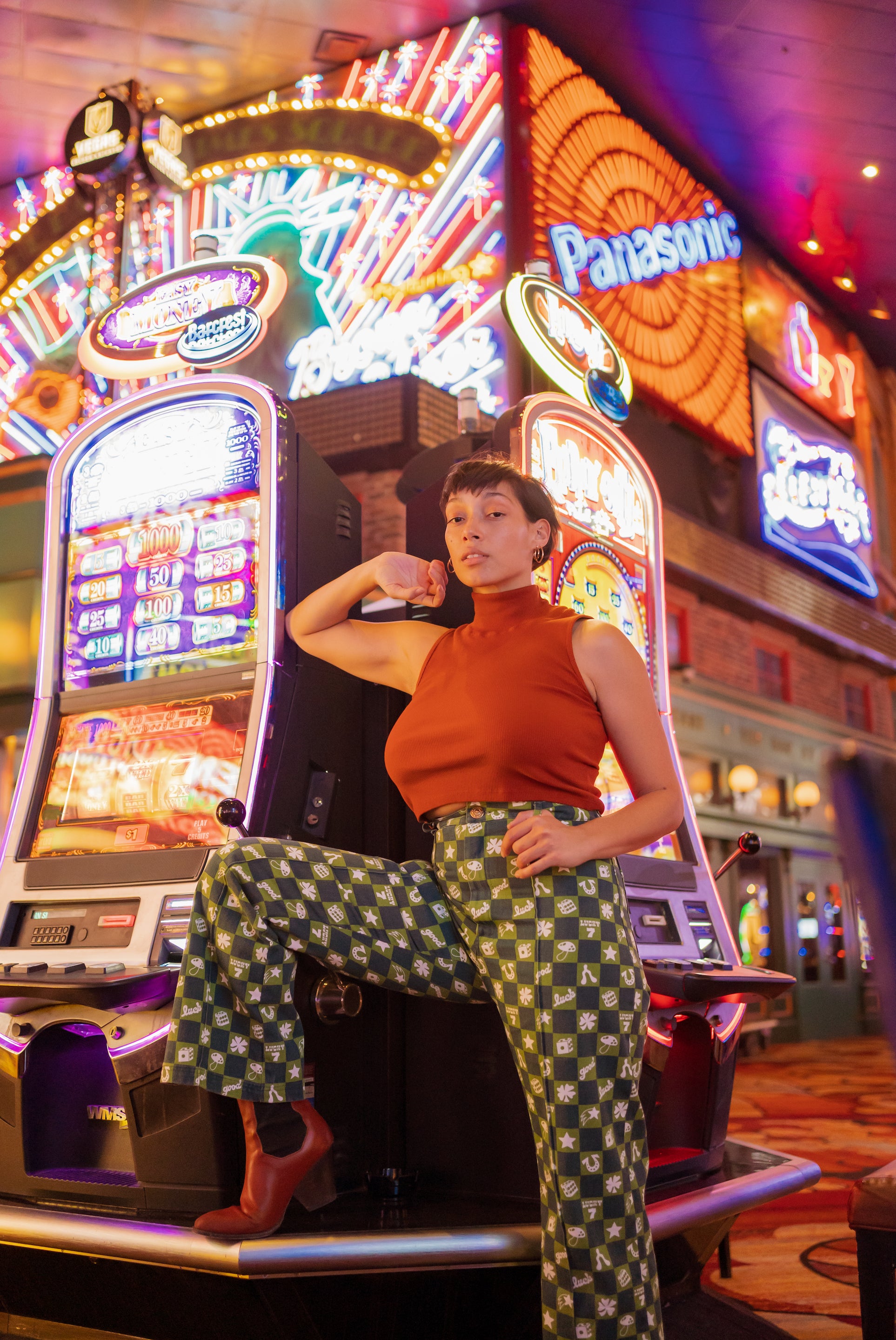 Tiara standing in front of slot machines wearing Lucky Western Pants in Spicy Mustard and Sleeveless Turtleneck in Burnt Terracotta.