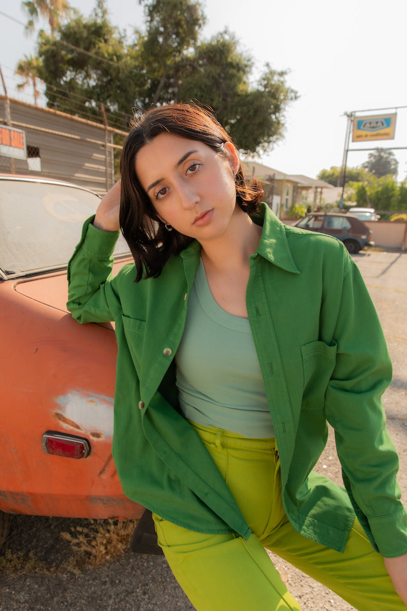 Betty is wearing Oversize Overshirt in Lawn Green, Tank Top in Sage Green and Western Pants in Gross Green