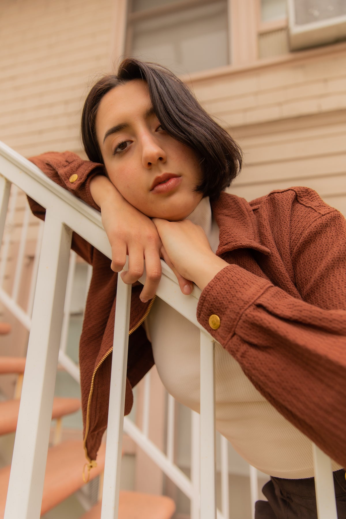 Betty is wearing Ricky Jacket in Fudgesicle Brown, Sleeveless Essential Turtleneck in Vintage Off-White, and Trouser Shorts in Espresso Brown