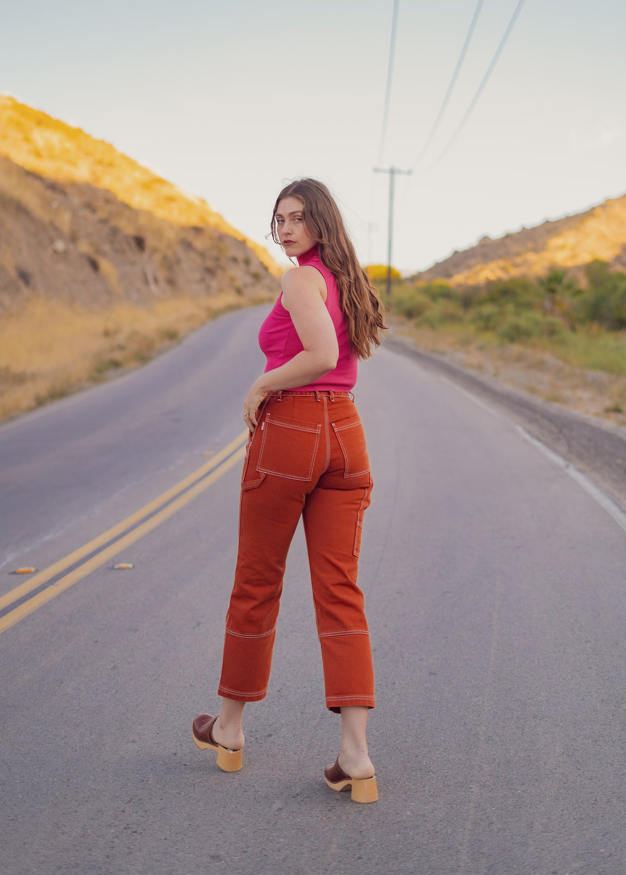 Allison is wearing Carpenter Jeans in Burnt Terracotta and Sleeveless Turtleneck in Hot Pink