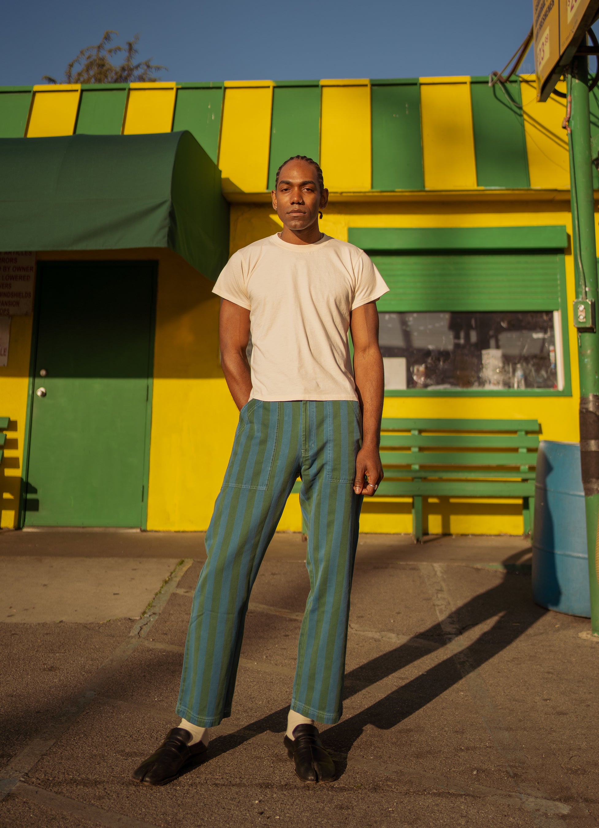 Jerrod is wearing Overdye Stripe Work Pants in Blue/Green and The Organic Vintage Tee in Vintage Off-White