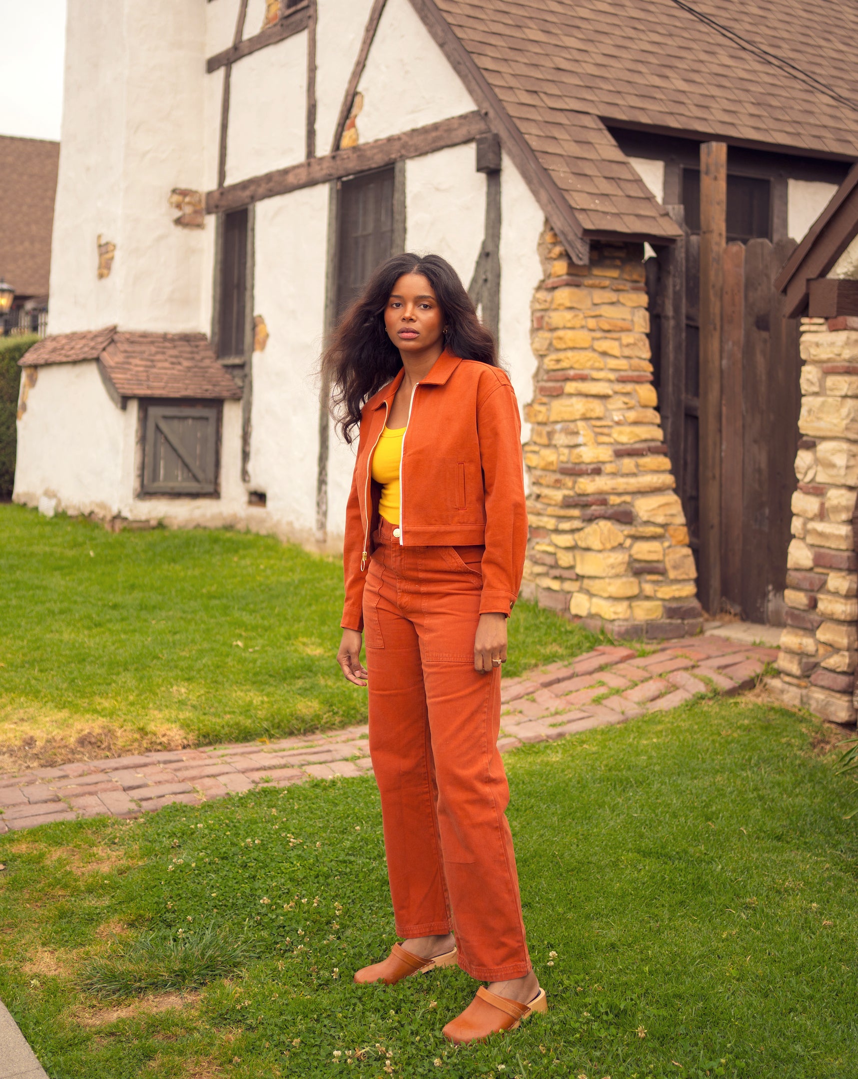 Kandia is wearing Ricky Jacket in Burnt Terracotta, Tank Top in Sunshine Yellow, and Work Pants in Burnt Terracotta