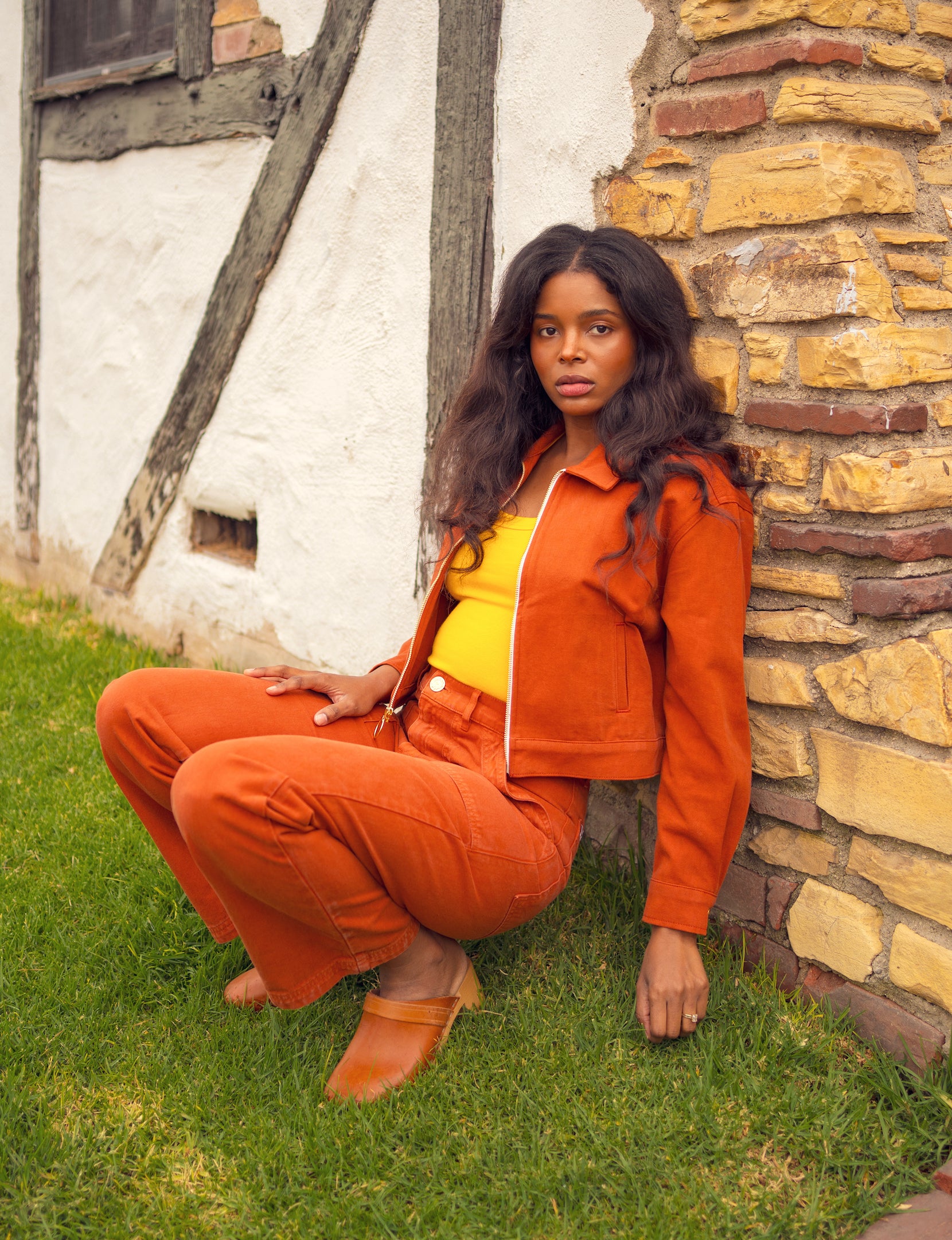 Kandia is wearing Ricky Jacket in Burnt Terracotta, Tank Top in Sunshine Yellow, and Work Pants in Burnt Terracotta