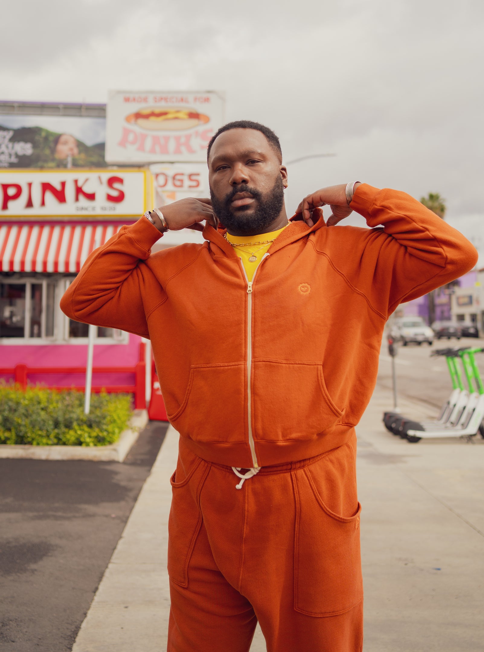 Elijah is wearing Cropped Zip Hoodie and Rolled Cuff Sweat Pants in Burnt Terracotta