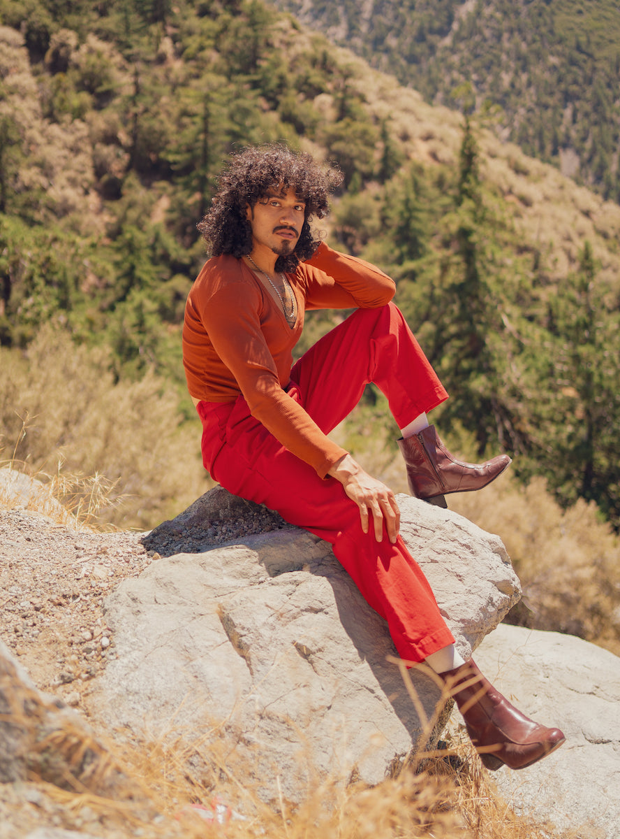 Jesse is wearing Heavyweight Trousers in Mustang Red and Long Sleeve V-Neck Tee in Burnt Terracotta