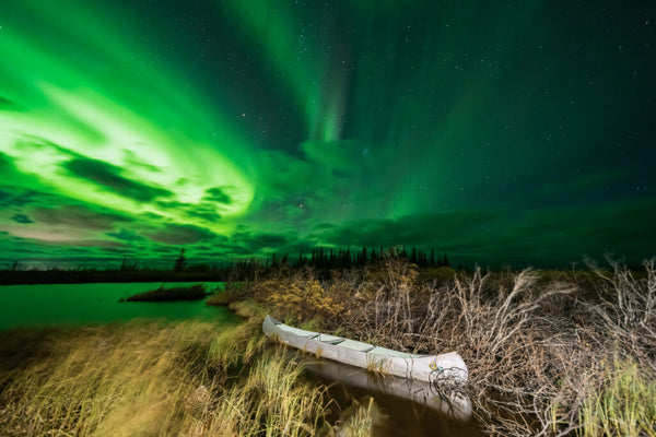 The aurora borealis captured by Vincent Ledvina seen over a lake with stars in the night sky.