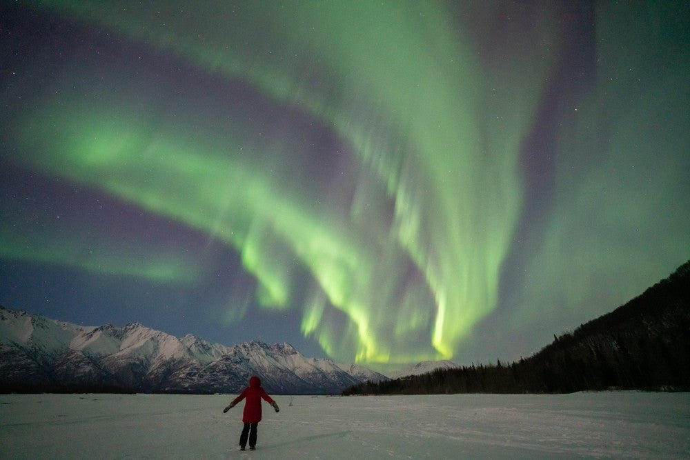 Person standing in front of the aurora in Alaska