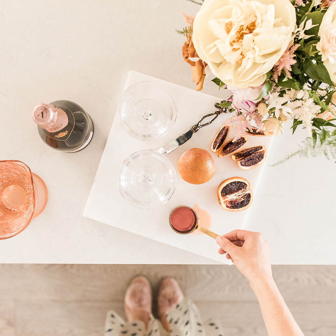 Sophie putting the ingredients together for an afternoon spritz, wearing Birdies Songbird slides in light pink