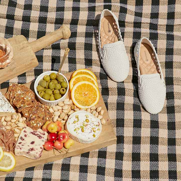 silver woven flats on picnic blanket with rosé and charcuterie board