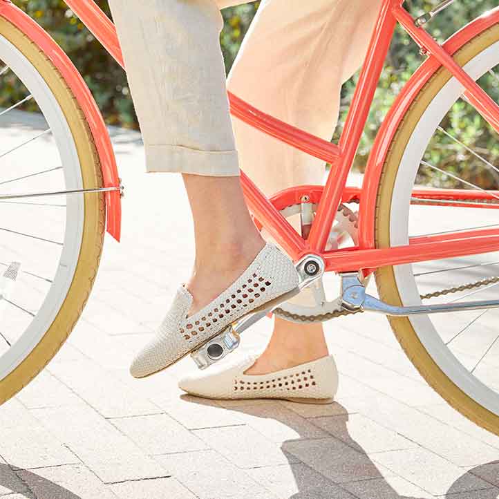 woman on a bike wearing white handwoven vegan leather flats