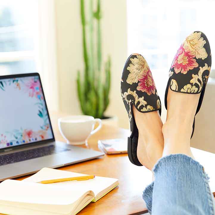 woman with feet up wearing vegan floral jacquard slides