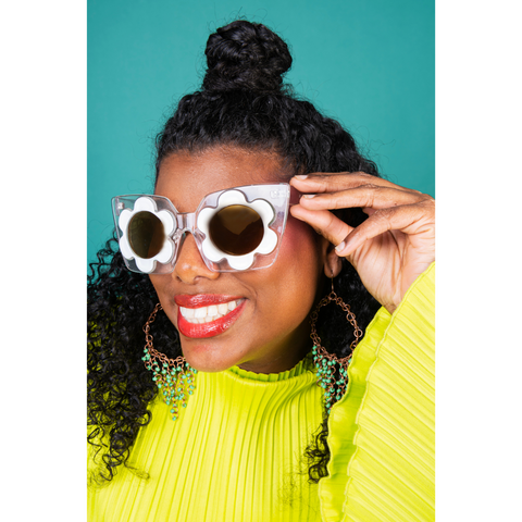 black woman with yellow sweater and flower sunglasses posing