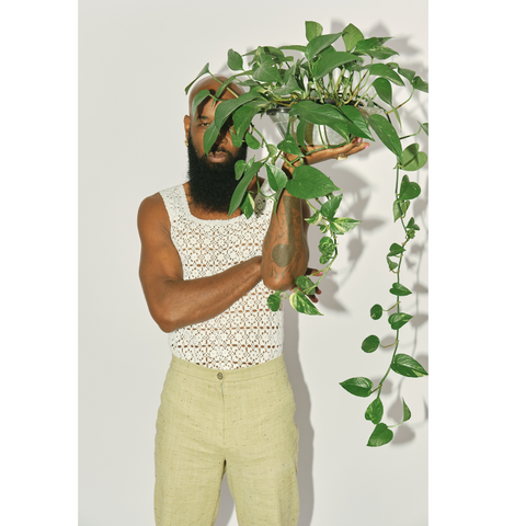 young black man holding a plant in front of his face