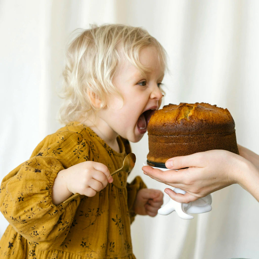 Kleines Kind, das in einen Kuchen beißt