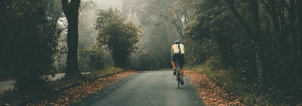 Ein Mann auf einem Fahrrad, der über eine Straße durch den Wald fährt