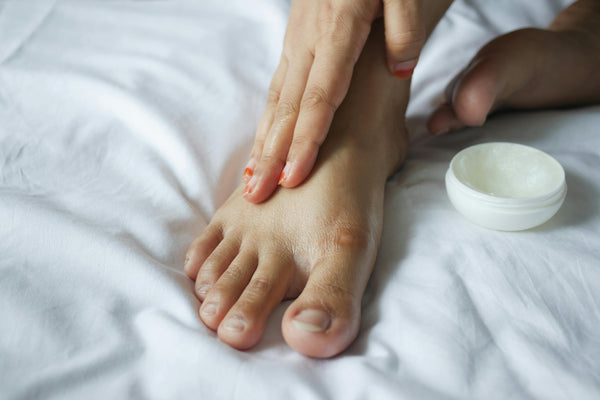 women self massaging her foot with balm