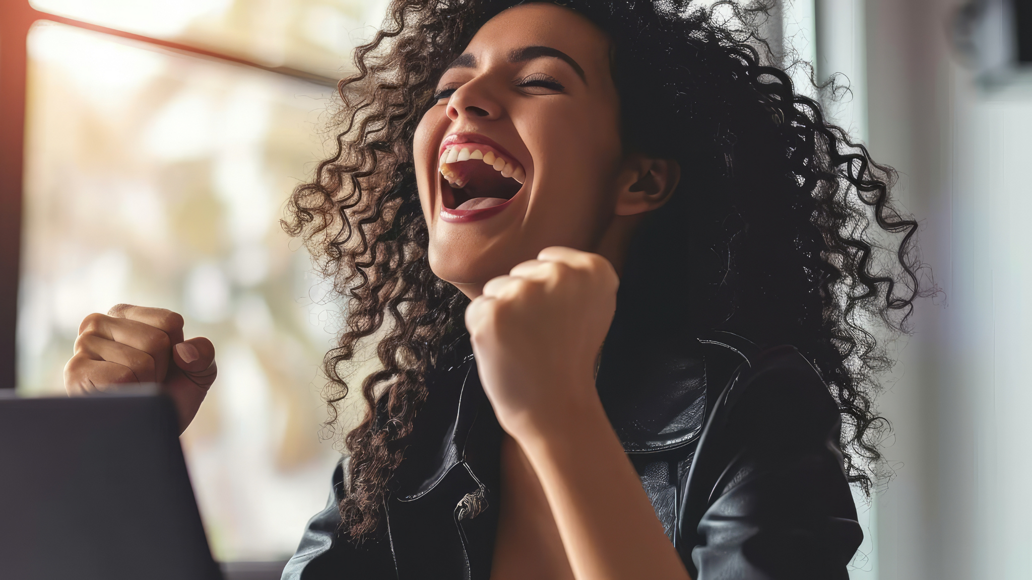 Excited woman sitting in front of a computer.