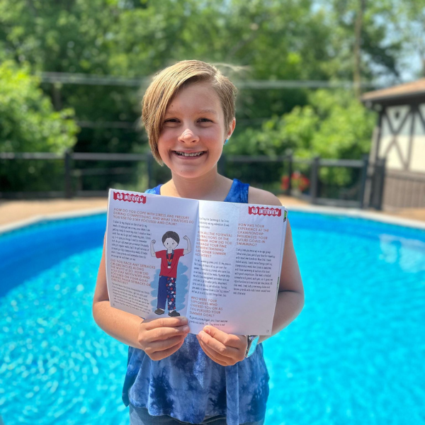 Photo of Gabby standing near a pool holding a copy of How's Your Summer Gonna Rock? guided journal