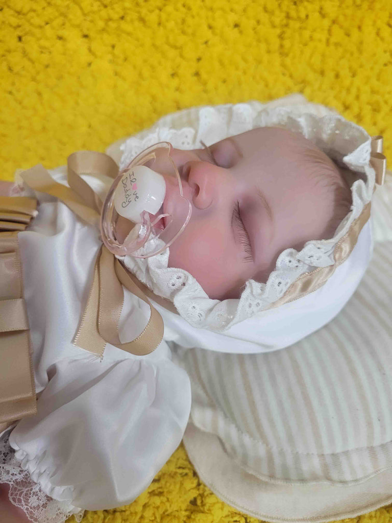 kaydora lifelike baby doll sleeping on a yellow carpet. She is so cute. Her eyelashes are so long and are hand-rooted.  She looks so real that many people thought she is a human baby.