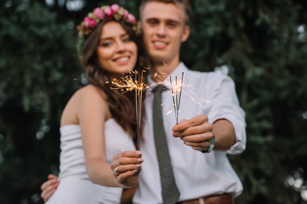 couple holding sparklers looking at the camera