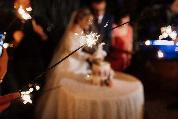 groom and bride is surrounded by people holding sparklers